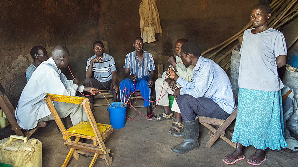 Drinkers enjoy a central pot of home-made alcohol in a kafunda
