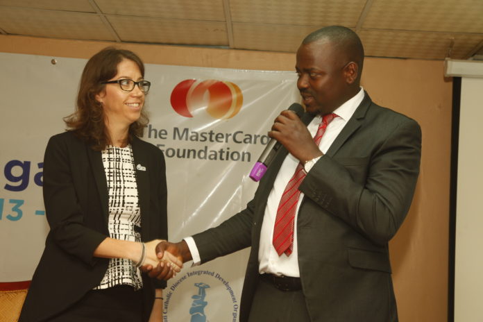 Elizabeth Pfifer greets State Minister for Microfinance Haruna Kasolo at lauch of CRS repoert yesterdat at Hotel Africana Kampla