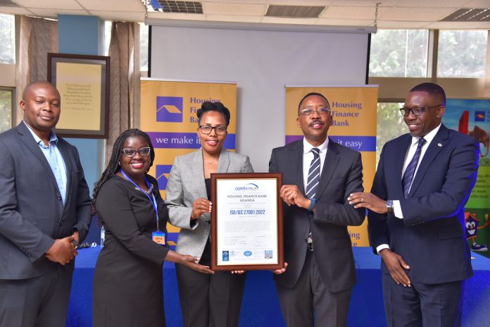 Top Housing Finance Bank and Certi-Trust executives pose for a group photo with the ISO certificate during the handover in Kololo